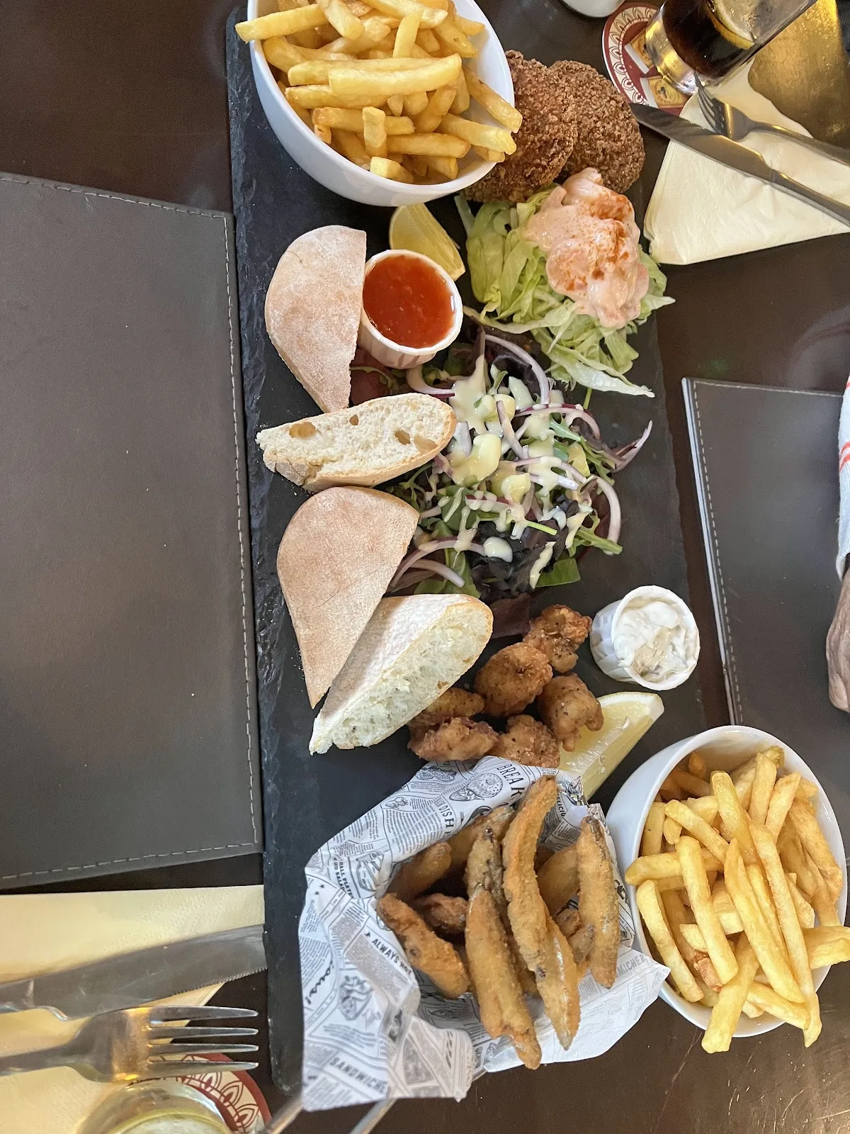 A sharing board at The Olive Leaf with whitebait, calamari, prawns, salad, bread and two bowls of chips